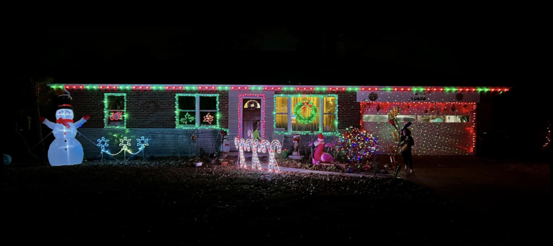 Holiday roofline lighting above a decorated yard